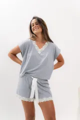 Pijama celeste de algodón con textura acanalada, compuesto por una remera de mangas cortas con escote en V y puntilla blanca, y un short con elástico en la cintura, lazo y terminación con puntilla.