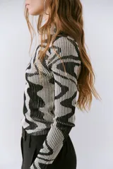 Polera de tejido de punto con diseño vanizado que combina tonos tierra y crema en un patrón abstracto de líneas onduladas. Presenta cuello alto, mangas largas y un ajuste entallado al cuerpo.