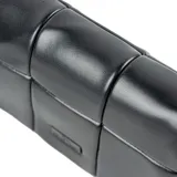 Bandolera negra de formato rectangular con diseño acolchado y solapa frontal. Cuenta con correa regulable, herrajes plateados y placa metálica con logo de la marca.