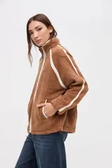 Campera de sherpa color marrón con diseño capitoneado, cierre frontal completo y detalles en color blanco. Presenta cuello alto, bolsillos laterales y puños elásticos.