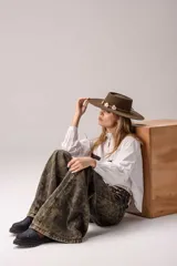 Camisa blanca de manga larga con cuello alto gorguera con volados y detalles de alforzas verticales en el frente. Cuenta con dos bolsillos en el pecho de pelo con estampado de vaca en tonos marrones y blancos.