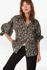 Camisa de lino italiano con estampado a rayas verticales irregulares, de corte holgado, cuello clásico, mangas abullonadas y cierre frontal con botones.