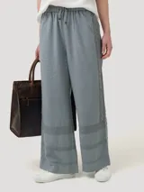 Pantalón de corte amplio y tiro alto, confeccionado en una mezcla de lino orgánico y viscosa. Presenta cintura elástica con cordón ajustable y detalles de encaje broderie tono sobre tono en los laterales y en el ruedo.