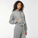 Buzo gris de corte cropped, con capucha, cierre frontal con cremallera y bolsillos tipo canguro.