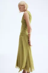 Vestido tobillero de punto color verde oliva, con escote redondo, manga japonesa y cuerpo entallado con costuras laterales fruncidas para un efecto drapeado. La falda tiene una caída suave y una costura diagonal fruncida en la cadera. Forrado.