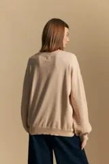 Sweater color crema con mangas abullonadas y puños elastizados. Presenta una textura tejida en relieve con patrón de ladrillos en el cuerpo y rayas horizontales en las mangas.