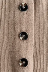 Saco ajustado de punto acanalado suave, con escote en V y botonadura frontal con cuatro botones oscuros. Modelo de cintura entallada con hombros ligeramente caídos y mangas largas con puños ceñidos.