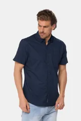 Camisa lisa de manga corta color crema, confeccionada en 100% algodón, con cuello abotonado y un bolsillo en el pecho.