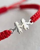 Pulsera de hilo rojo trenzado en macramé, con dije central de plata 925 con diseño de dos nenas tomadas de la mano y cierre regulable.