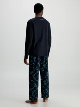 Conjunto de pijama Calvin Klein compuesto por una remera de manga larga negra con logo CK en el pecho y un pantalón largo negro con estampado del logo CK en azul.