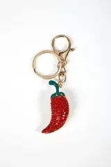 Llavero metálico dorado con dije en forma de ají morrón, adornado con pedrería roja brillante y tallo verde esmaltado.