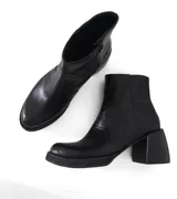 Bota corta de cuero negro con textura tipo reptil, taco cuadrado y plataforma. Cuenta con cierre lateral interno.