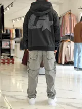 Canguro oversize gris con capucha y gran estampado gráfico trasero en tono más oscuro.