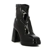 Bota corta de mujer color negro, con acabado charol brillante. Presenta un taco ancho y alto, y una plataforma delantera. El caño es ajustado, tipo calcetín, con textura elástica en el borde superior.
