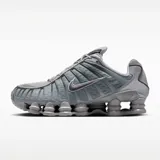 Championes Nike Shox TL en tonos gris lobo y gris hierro, con diseño de amortiguación Shox en la suela y detalles de malla en la parte superior.