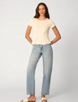 Remera blanca de manga corta con cuello redondo, confeccionada en una mezcla de modal, poliéster y elastano. Presenta un diseño con alforzas verticales en el frente que aportan estructura y una silueta relajada.