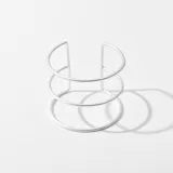 Brazalete rígido plateado de metal con tres aros.