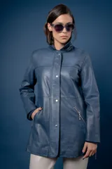 Campera de cuero en tono azul con efecto gastado, de corte recto y largo medio. Presenta cuello camisero, cierre frontal con botones a presión ocultos bajo una solapa y bolsillos laterales con cierre metálico.