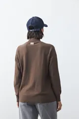 Polera de tejido de punto color gris oscuro, con cuello alto y diseño de rombos en relieve en el frente. Presenta un calce relajado con terminaciones en rib en cuello, puños y ruedo.