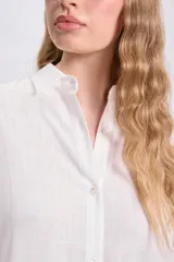 Vestido camisero largo color blanco, con cuello mao, abotonadura frontal y mangas largas abullonadas con puños camiseros.