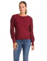 Buzo de tejido lurex marca Nanette, con cuello redondo y mangas largas con diseño plisado. Presenta puños ajustados con aplique de botones decorativos.