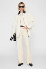 Chaqueta de corte relajado de algodón color blanco crudo, con cuello camisero a contraste en color negro, cierre frontal con cremallera, bolsillos aplicados y puños con botón, de inspiración utilitaria.