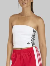 Top strapless Adidas de diseño entubado, color blanco, con las tres tiras características en color negro en los laterales y el logo del trifolio bordado en el bajo.