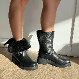 Bota de caña media confeccionada en cuero vacuno, con interior forrado en corderito. Presenta una suela de goma tipo track con plataforma y detalle de tira con hebilla metálica en la parte superior de la caña.