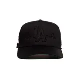 Gorra negra con visera curva, bordado frontal en relieve con las letras "LA" y las frases "Mi Casa" y "Su Casa".