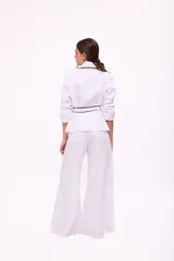 Pantalón de lino blanco de corte wide leg, con diseño amplio y costuras pespunteadas a contratono.
