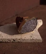 Cinto de cuero marrón camel con hebilla metálica ancha adornada con una piedra natural de amatista facetada.