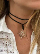 Gargantilla negra de doble tira con dije plateado en forma de sol.