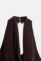 Vestido corto de cuello halter con escote drapeado y espalda descubierta. Presenta un diseño con frunces en la cintura y un bajo asimétrico con terminaciones en punta.