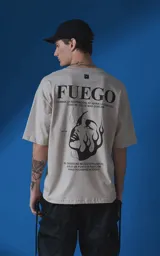 Remera de manga corta y cuello redondo con calce oversize, color beige con estampa gráfica en negro que incluye texto y un rostro femenino estilizado con llamas.