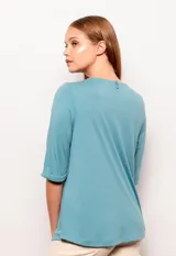 Remera negra de manga corta con cuello redondo y detalle de volados en forma de triángulo invertido en la parte delantera.