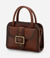 Cartera pequeña de mano con diseño estructurado, confeccionada en poliuretano color marrón con acabado envejecido. Cuenta con tapa frontal decorada con una hebilla metálica, cierre principal con cremallera, asa de mano rígida y correa larga ajustable y desmontable.