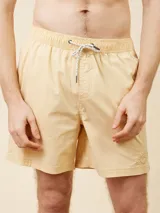 Short de baño tipo volley color amarillo claro, con cintura elástica y cordón ajustable. Presenta un diseño liso con un pequeño logo bordado en la parte inferior de la pierna izquierda.