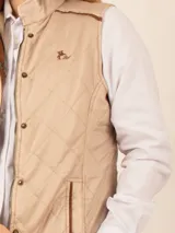 Chaleco beige capitoneado con cierre frontal y cuello alto.