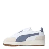 Championes urbanos Puma modelo Shuffle Downtown OG, de diseño retro con base blanca, detalles en gris azulado y puntera de gamuza en tono beige. Cuenta con suela de goma color caramelo y logo de la marca en dorado.