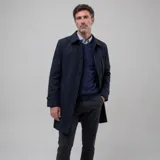 Gabardina impermeable de corte clásico en color azul marino, con cierre frontal de botones, cuello camisero y ajuste en los puños. Cuenta con forro interior a cuadros y múltiples bolsillos internos.