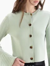 Cardigan negro de tejido de punto semi liviano, con calce al cuerpo, escote redondo y cierre frontal con botones. Mangas largas con puños godet acampanados que aportan volumen.