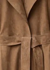 Abrigo largo de piel caprino con diseño recto, cuello con solapas de muesca, cierre frontal con botones, cinturón tipo batín y bolsillos laterales.
