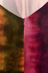 Vestido midi de cuello halter y escote en V, con diseño tie-dye en tonos fucsia, borgoña y verde. Presenta un nudo decorativo en el delantero, espalda descubierta y abertura frontal en el bajo.