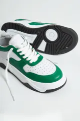 Zapatillas deportivas de cuero, combinadas en blanco y verde, con base negra.