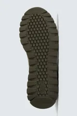 Zapatilla deportiva color verde militar, con parte superior de múltiples piezas que combinan piel y serraje. Presenta horma redonda y suela dentada en color crema con base marrón.