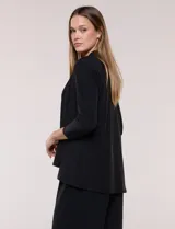 Cardigan negro de tejido elastizado con textura lisa, frente abierto sin botones y solapas amplias de caída drapeada. Cuenta con mangas tres cuartos y ruedo asimétrico.