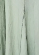 Vestido midi de color verde menta, con cuello en pico, mangas cortas y diseño evasé. Presenta costuras verticales decorativas a lo largo de la prenda y cierre de cremallera en la parte posterior.