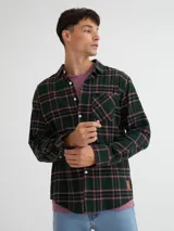 Camisa de manga larga confeccionada en viyela de algodón, con patrón de cuadros escoceses en tonos verde oscuro, negro y rosado. Presenta un bolsillo en el pecho y botones blancos.