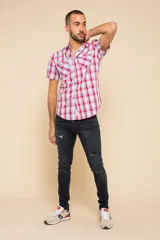 Camisa de manga corta con estampado de cuadros en tonos verdes, azules y blancos. Presenta cuello clásico, cierre frontal con botones y dos bolsillos delanteros con solapa.