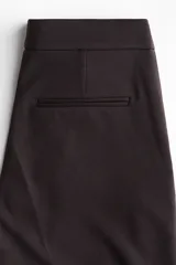 Pantalón sastrero de corte acampanado, con cierre frontal, botón oculto y corchetes. Presenta bolsillos al bies, bolsillos traseros ribeteados y pliegues marcados tanto en la parte delantera como en la trasera.